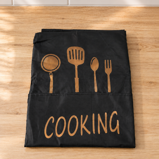 Fresh waterproof black kitchen apron with large front pocket, golden utensil print, and COOKING script