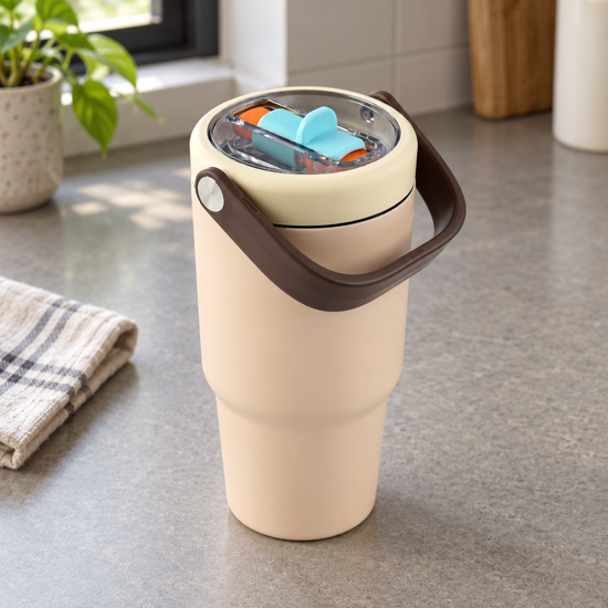 T&CO warm peach vacuum insulated travel tumbler with mocha brown swing carry handle and clear lid with blue-and-orange sipper