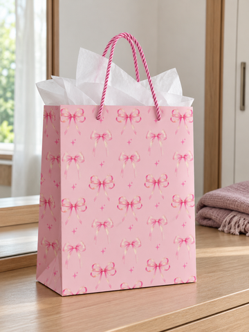 Small pastel pink gift bag printed with orderly rows of pink ribbon bows, pink braided rope handles, and white tissue paper