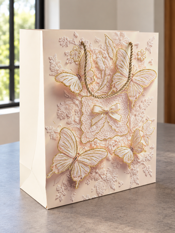 Medium blush pink butterfly bow lace gift bag with gold glitter wings and rope handles