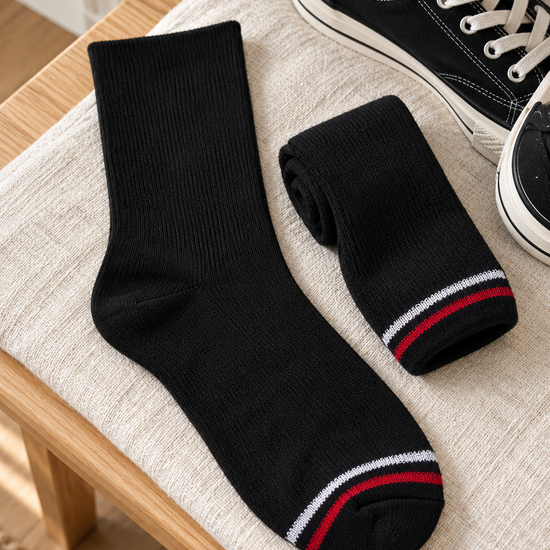 Men's athletic ribbed cotton crew socks in solid jet black with sporty red and white toe stripe accent resting beside casual canvas sneakers