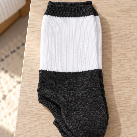 Men's premium ribbed knit cotton crew socks in two-tone colorblock styling with crisp white leg panel and heather charcoal foot folded on light wood surface