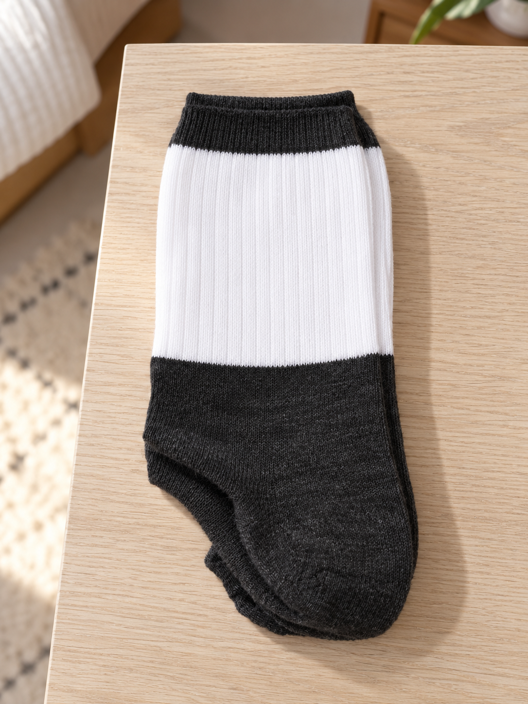 Men's premium ribbed knit cotton crew socks in two-tone colorblock styling with crisp white leg panel and heather charcoal foot folded on light wood surface