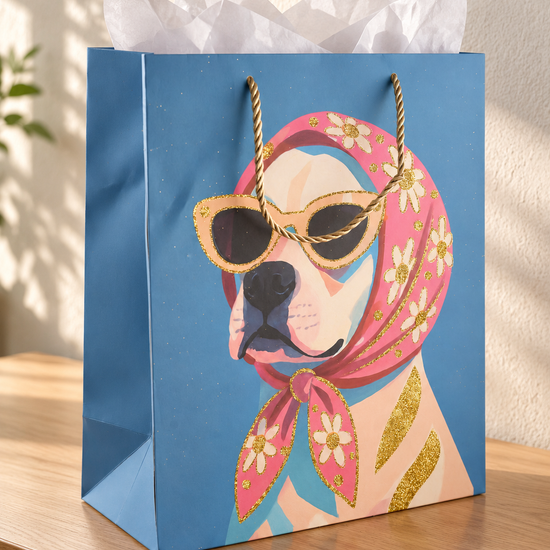 Retro Rosie medium sky blue paper gift bag featuring dog in floral headscarf and sunglasses with twisted gold cord handles