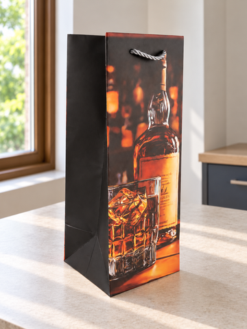 Whiskey on the Rocks single bottle paper gift bag featuring a crystal tumbler of scotch on ice beside a spirits bottle on a wooden bar counter with silver rope handles