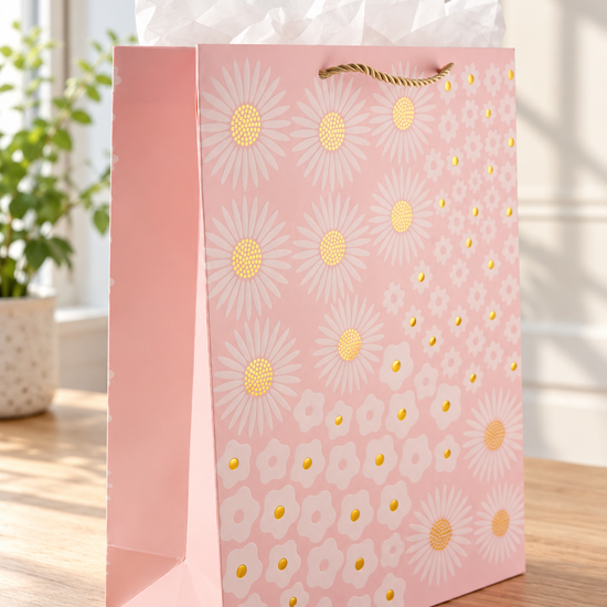 Golden Daisy Bloom large blush peach paper gift bag featuring white daisy blossoms with radiant gold foil stamped centers and twisted gold rope handles