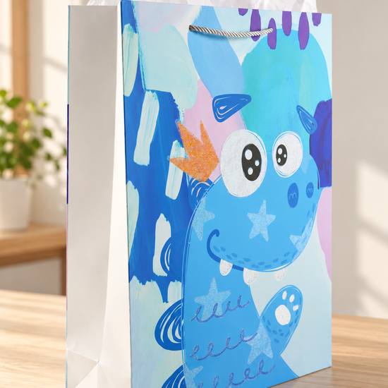 Dino King extra large kids paper gift bag featuring a friendly smiling blue dinosaur wearing an orange glitter crown with silver rope cord handles