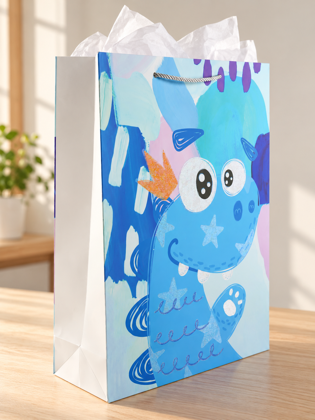 Dino King extra large kids paper gift bag featuring a friendly smiling blue dinosaur wearing an orange glitter crown with silver rope cord handles