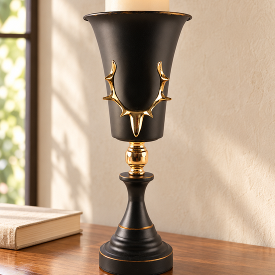 Tall matte black trumpet goblet pillar candle holder featuring a raised gold antler emblem and polished gold stem connector