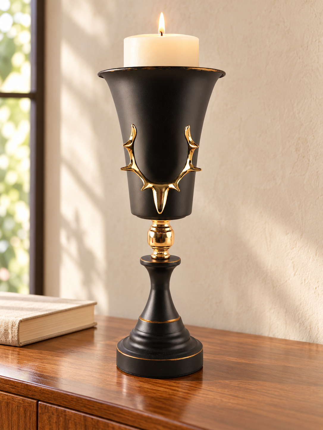 Tall matte black trumpet goblet pillar candle holder featuring a raised gold antler emblem and polished gold stem connector
