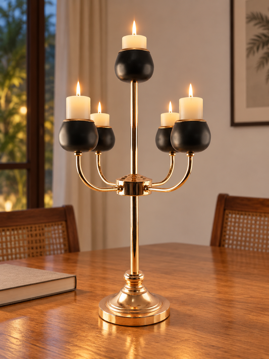 5-arm polished gold and matte black candelabra centerpiece with lit candles on dining table