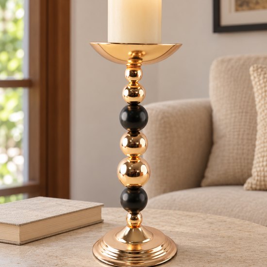 Modern stacked gold and black sphere beaded pillar candle holder with lit pillar candle