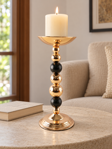 Modern stacked gold and black sphere beaded pillar candle holder with lit pillar candle