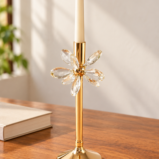 Polished gold taper candlestick with six faceted crystal flower petals on polished wood table