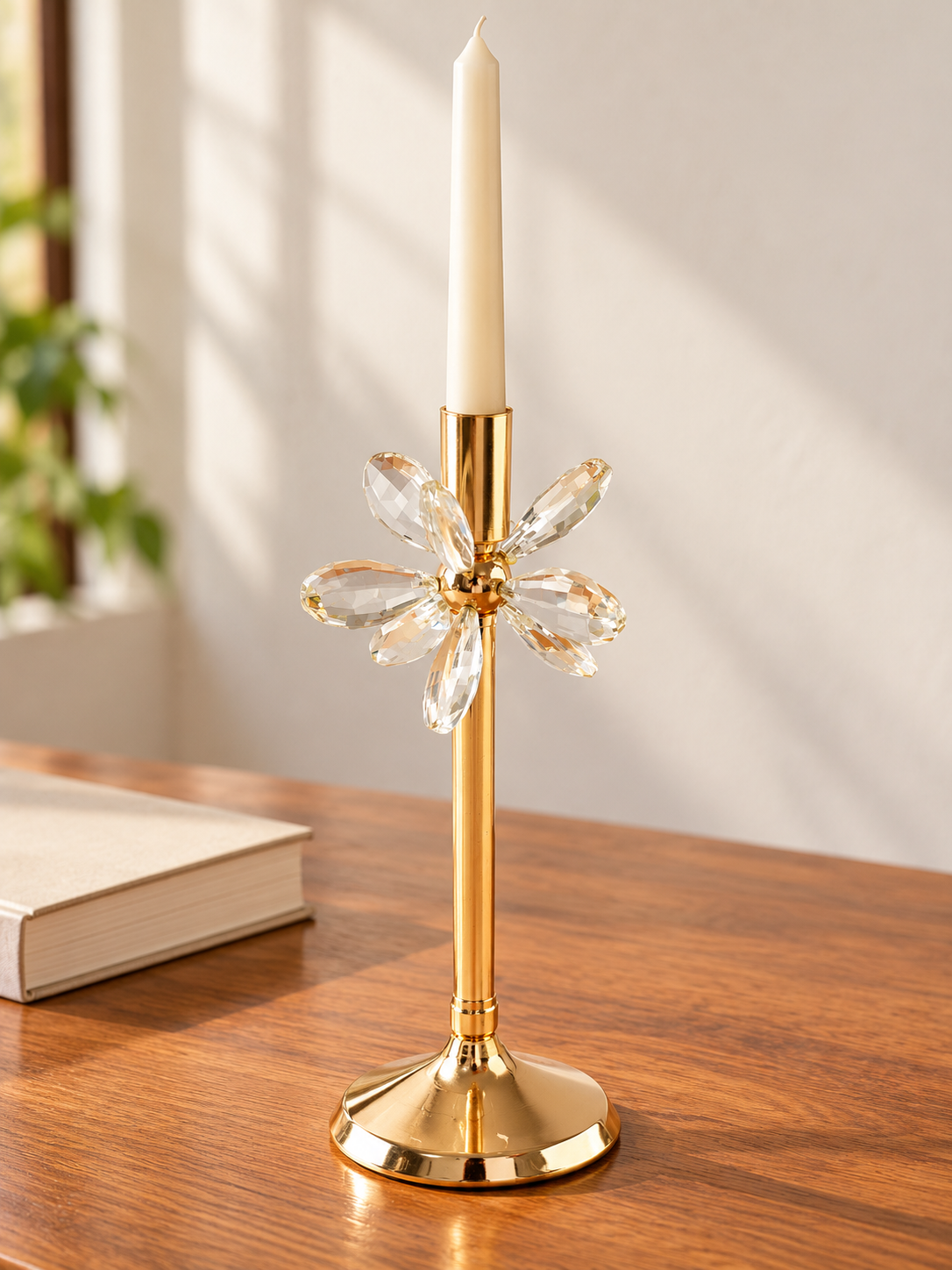 Polished gold taper candlestick with six faceted crystal flower petals on polished wood table