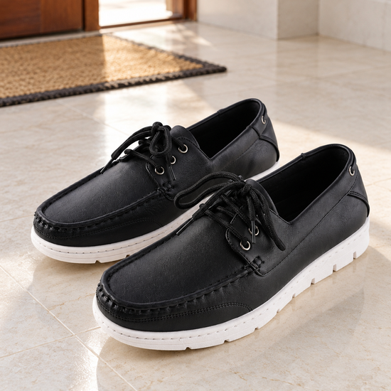 Men's sleek all-black faux leather lace-up boat shoes with 360-degree lacing, metallic silver grommets, and contrasting white rubber sole