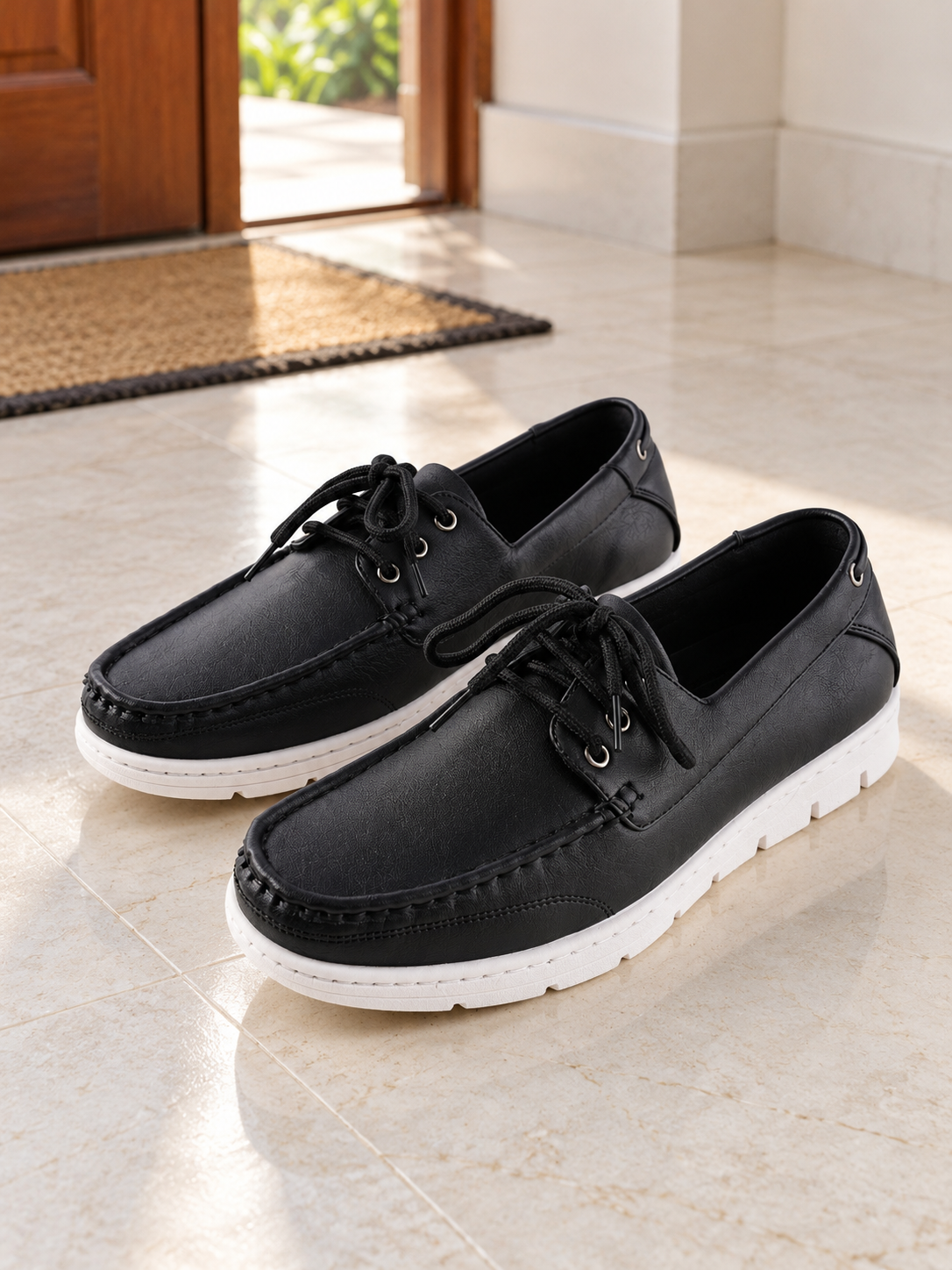 Men's sleek all-black faux leather lace-up boat shoes with 360-degree lacing, metallic silver grommets, and contrasting white rubber sole