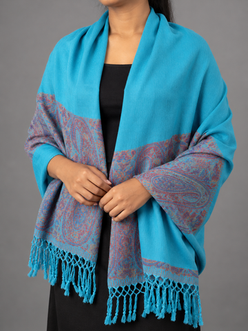 Women's vibrant cerulean turquoise blue pashmina shawl featuring smooth woven body, rich wine purple and maroon paisley tapestry border, and turquoise tassels