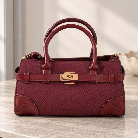 Nuvaara women's East-West structured wine burgundy twill satchel handbag with smooth vegan leather trim, front belt strap, and gold turn-lock plate