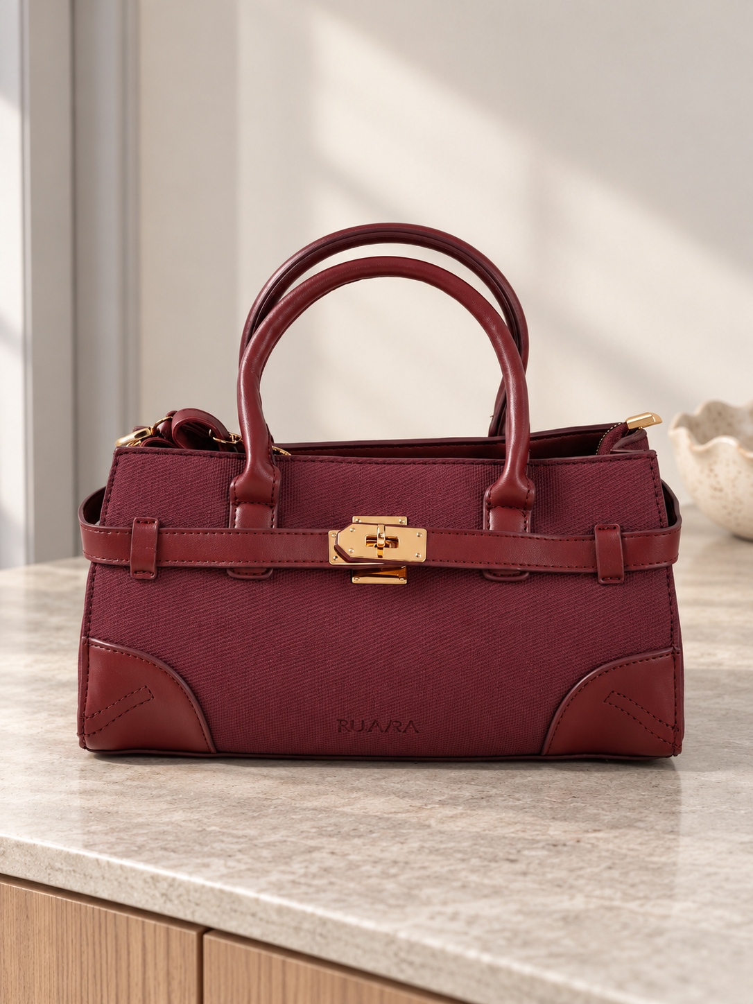 Nuvaara women's East-West structured wine burgundy twill satchel handbag with smooth vegan leather trim, front belt strap, and gold turn-lock plate