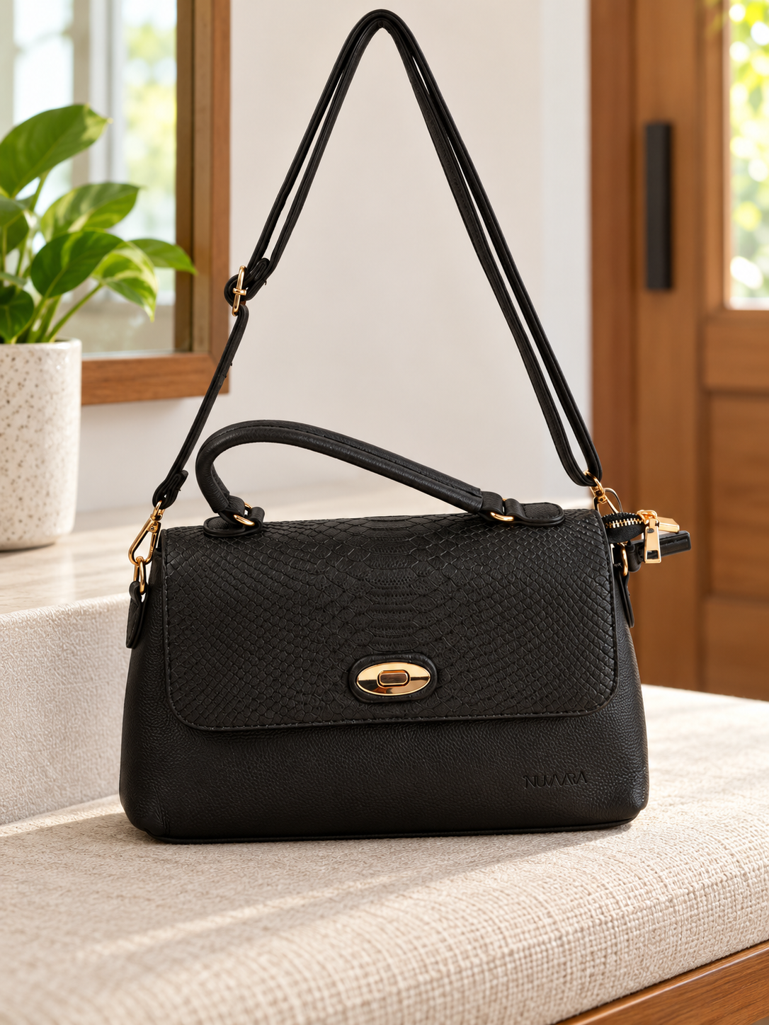 Nuvaara women's structured black shoulder bag featuring snake-embossed front flap, gold oval turn-lock clasp, arched top handle, and crossbody strap