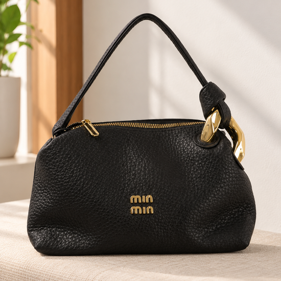 Nuvaara women's black pebbled vegan leather shoulder handbag featuring an asymmetric knotted handle accented with chunky polished gold-tone metal chain link