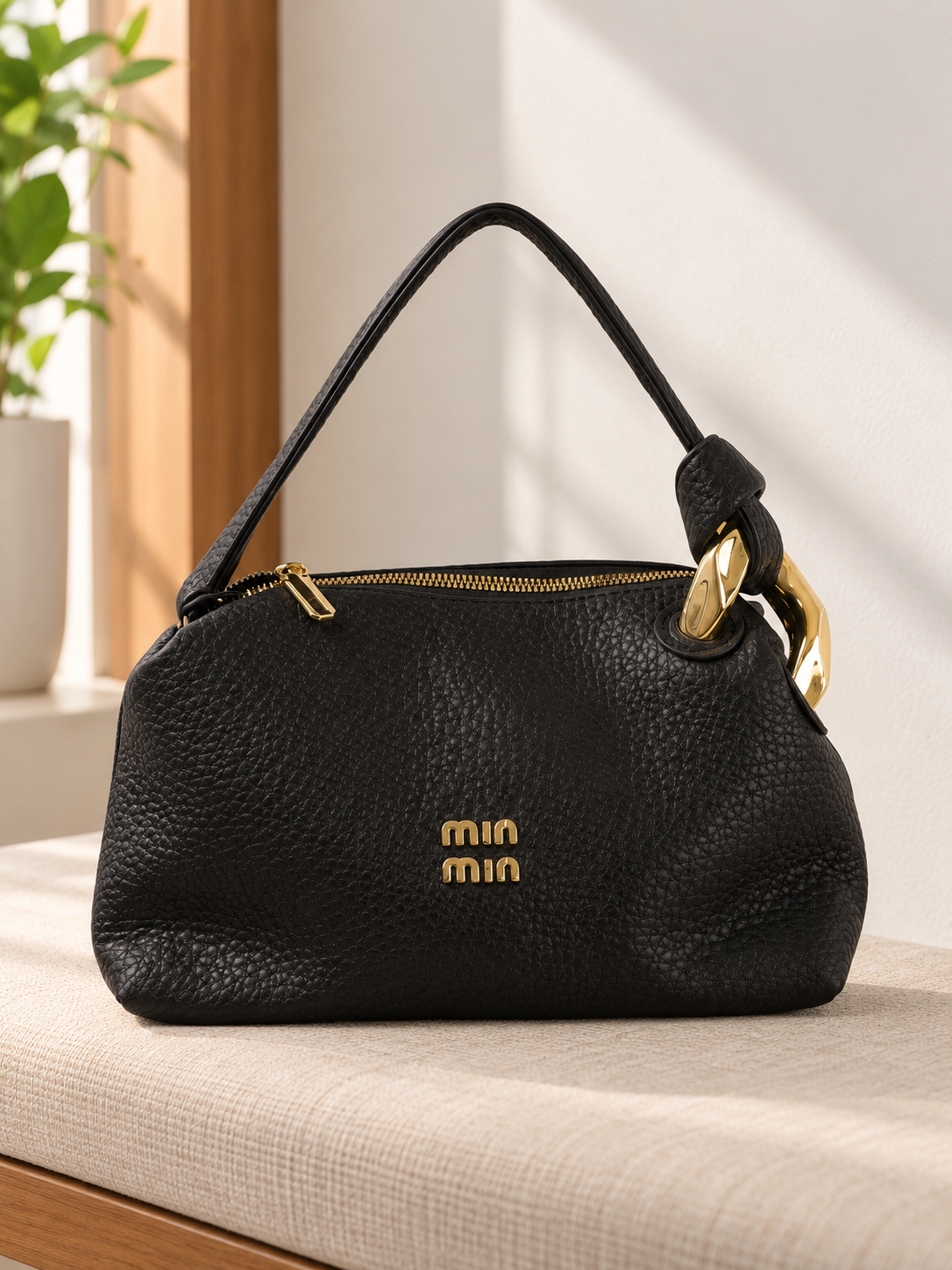 Nuvaara women's black pebbled vegan leather shoulder handbag featuring an asymmetric knotted handle accented with chunky polished gold-tone metal chain link