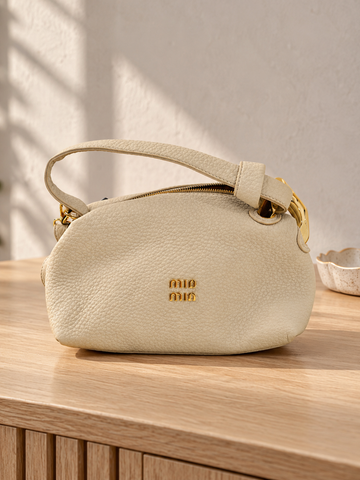 Nuvaara women's ivory off-white pebbled vegan leather shoulder handbag featuring an asymmetric knotted handle accented with chunky polished gold-tone metal chain link