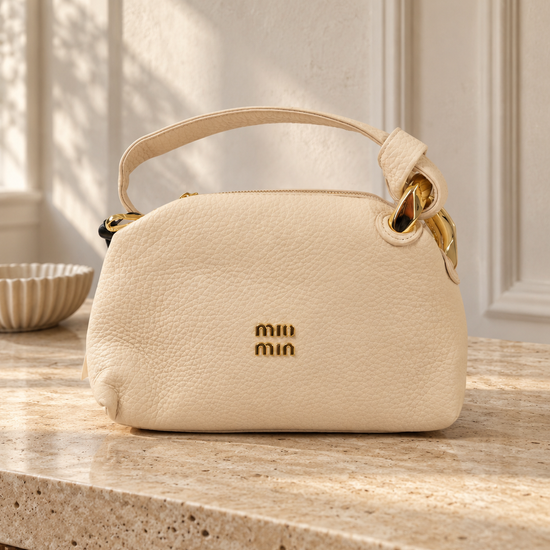 Nuvaara women's soft cream pebbled vegan leather shoulder handbag featuring an asymmetric knotted handle accented with chunky polished gold-tone metal chain link