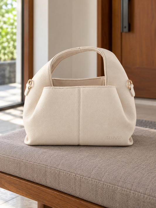 Nuvaara women's soft cream pebbled vegan leather slouchy curved dome satchel handbag with center vertical seam, dual arched handles, and debossed logo