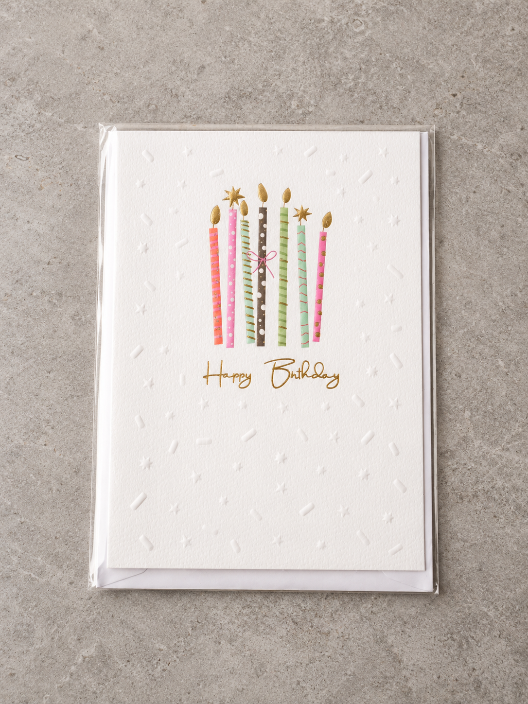 Embossed Happy Birthday greeting card featuring colourful patterned birthday candles tied with a pink bow and gold foil flames