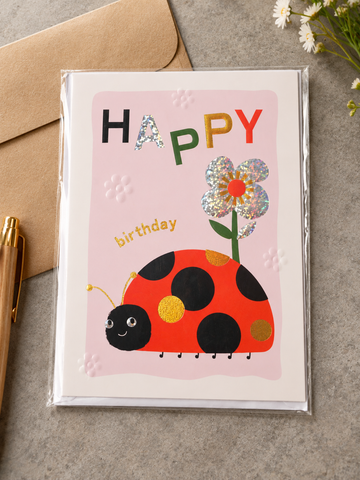 Kids Happy Birthday greeting card with smiling ladybug, googly eyes, holographic silver flower, and kraft envelope