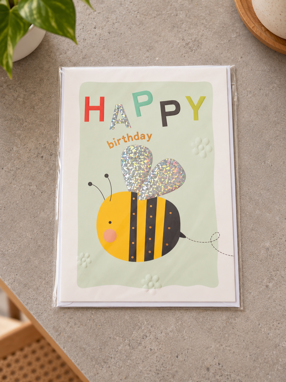 Kids Happy Birthday greeting card featuring a cheerful bumblebee with holographic glitter wings on pastel green