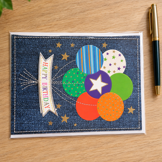 Festive denim birthday greeting card with stitched Happy Birthday banner and colorful balloon cluster