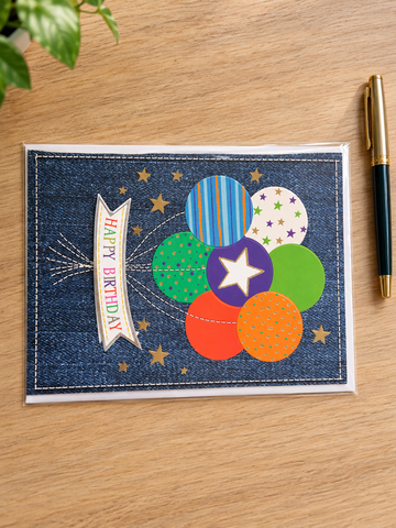 Festive denim birthday greeting card with stitched Happy Birthday banner and colorful balloon cluster