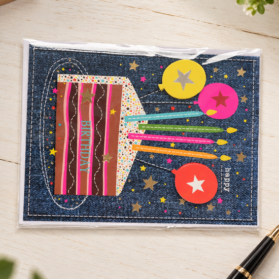 Denim textured birthday greeting card with striped birthday cake, burning candles, and star balloons