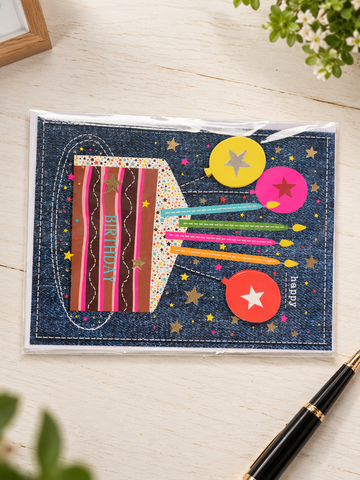Denim textured birthday greeting card with striped birthday cake, burning candles, and star balloons