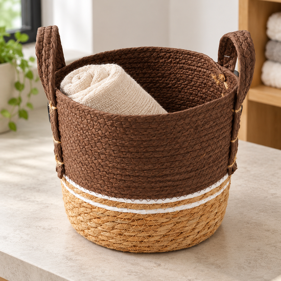 Small brown and beige two-tone woven seagrass storage basket with white accent stripe and handles
