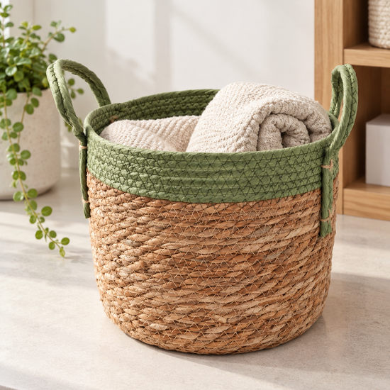 Small natural woven straw storage basket featuring a sage green braided top rim and dual handles