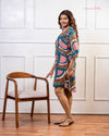 Front view of model smiling wearing Cinnamon Isle teal blue and coral pink mosaic tunic dress