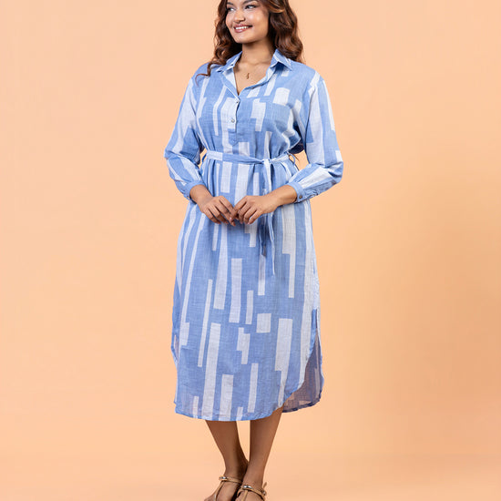 Front view of model with hands in pockets wearing Cinnamon Isle blue domino print belted shirt dress