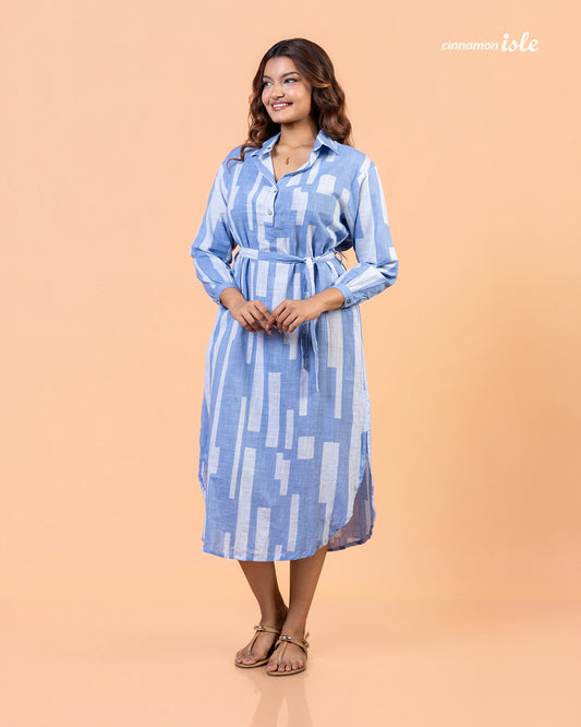 Front view of model with hands in pockets wearing Cinnamon Isle blue domino print belted shirt dress