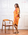Cinnamon Isle Women's Sunset Orange Tropical Print Shirt Dress side profile standing near armchair