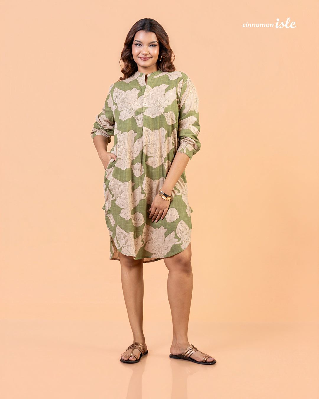 Cinnamon Isle Women's Olive Green Leaf Print Curved Hem Tunic Dress front view with hands in pockets